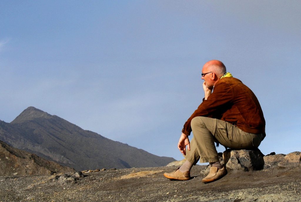 A man pauses as if contemplating no new short term rental licenses while on the top of a mountain.